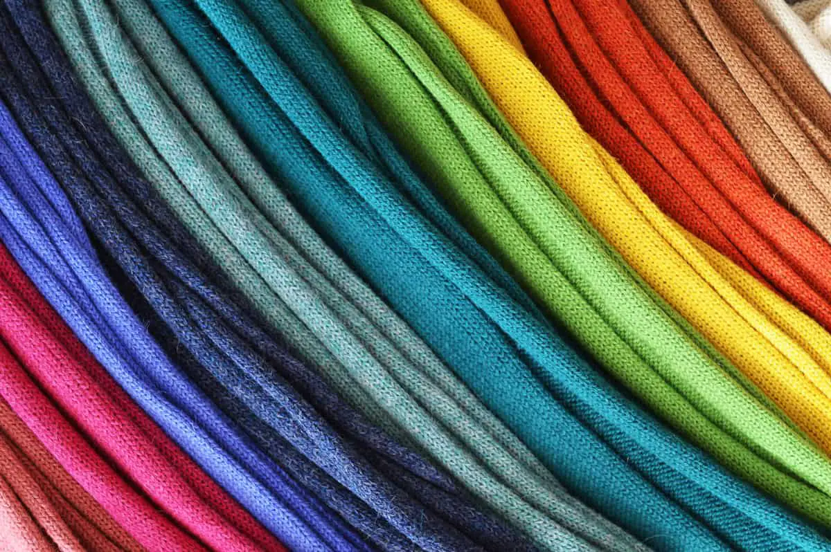 Alpaca woolen scarves folded and piled up in order of color. The picture is a close-up so that it looks like a rainbow.