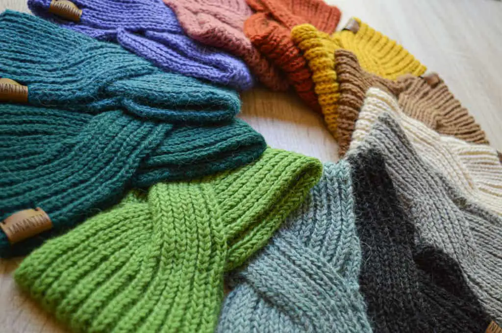 100% alpaca woolen headbands made with an English stitch. Different colors of wool. They are lined up in a circle.