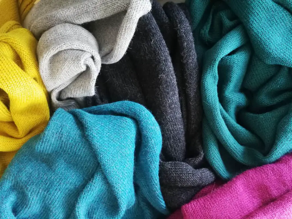 Garments made with 100% alpaca wool. Not folded, but put together on a pile. Noncholant, Six different colors: yellow, gray, blue, dark grey, pink and green.